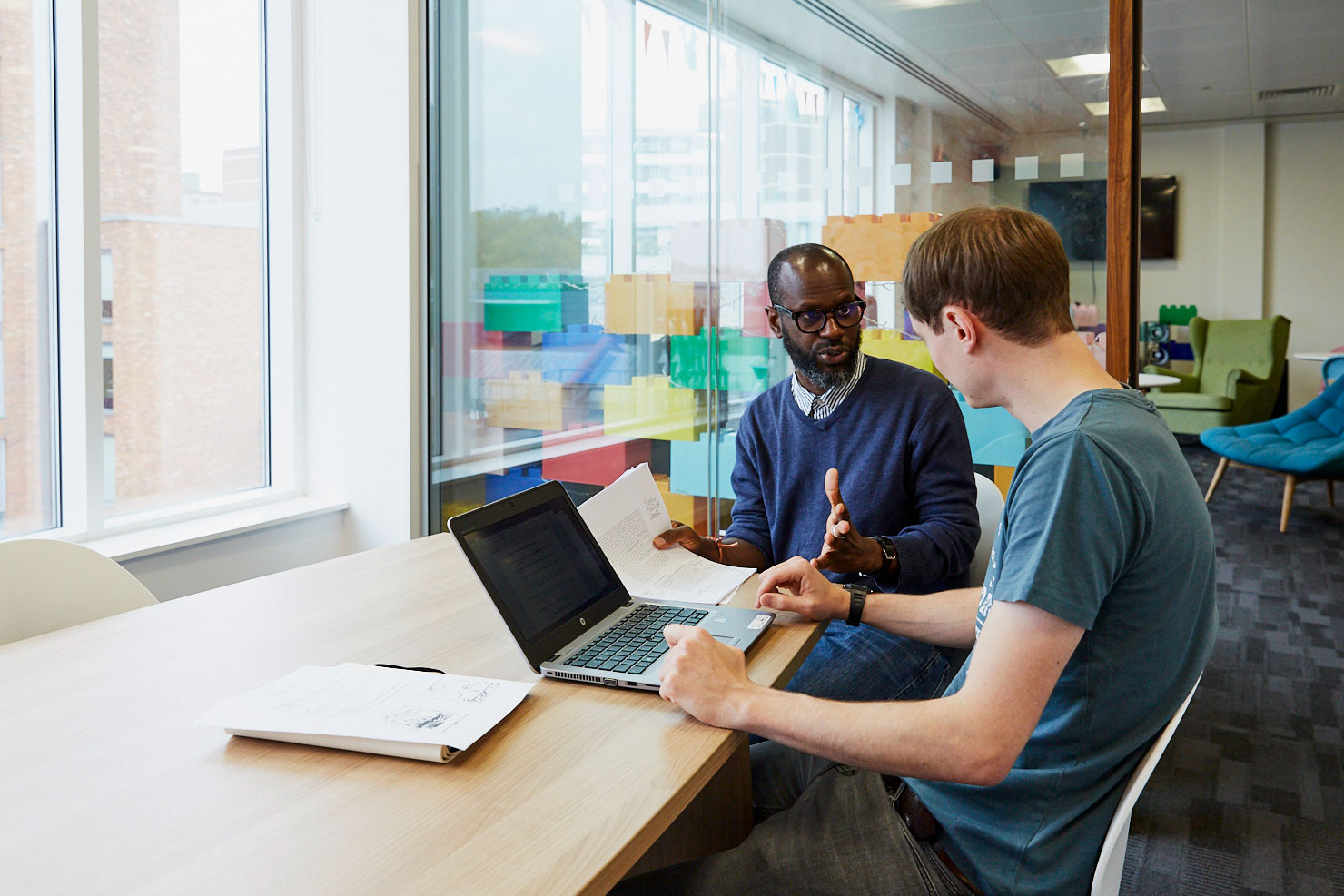 Two men have discussion near laptop computer